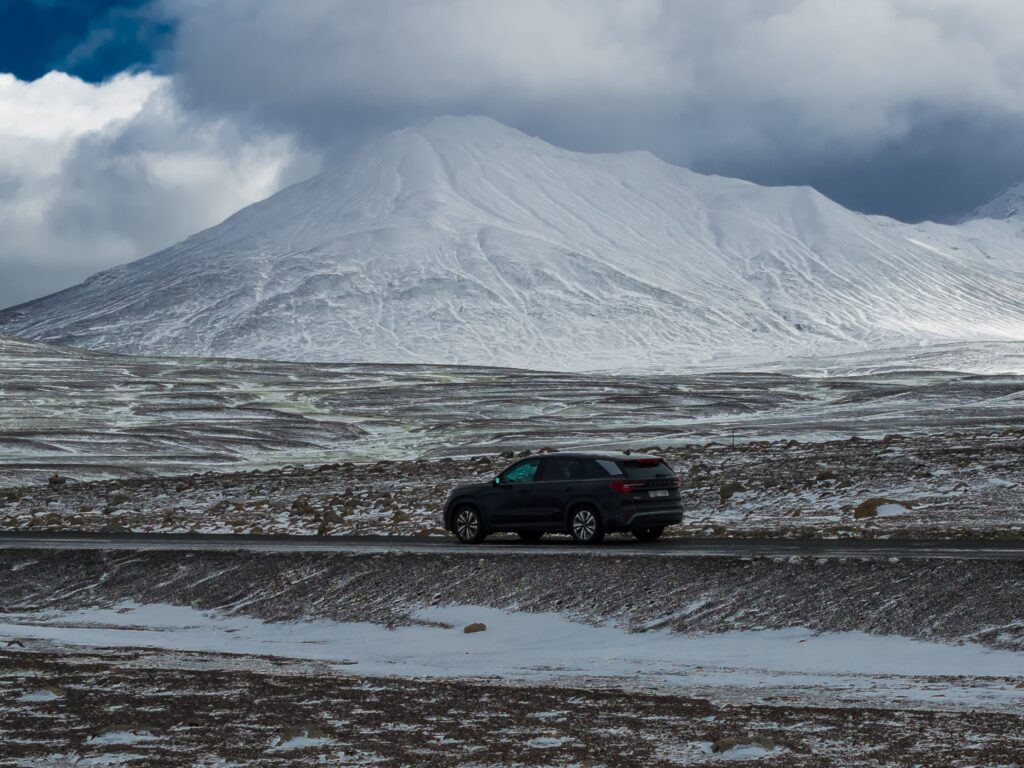 4x4 rental car driving on snowy road near mountains in Iceland winter landscape — Thrifty Car Rental Iceland self-drive adventure.