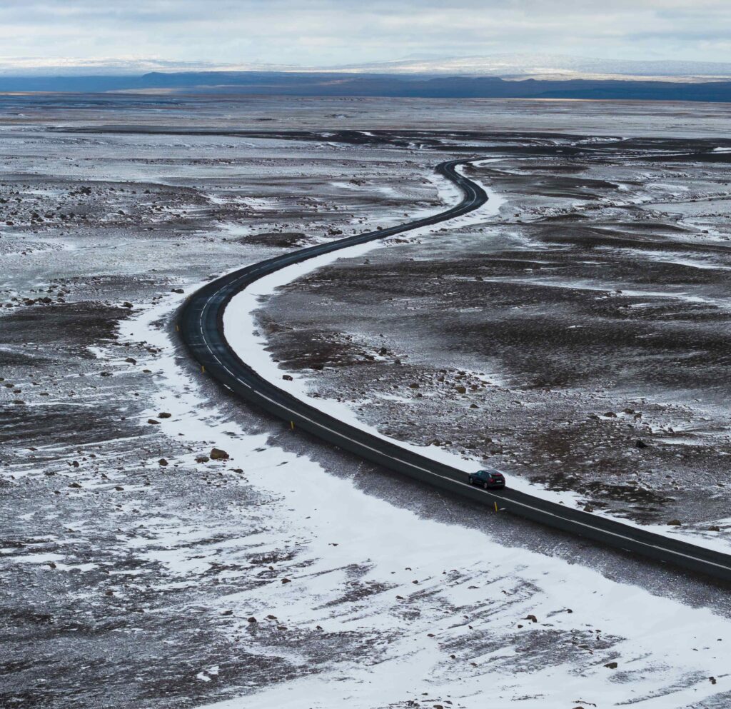 Car driving on snowy road near Egilsstaðir East Iceland during winter — self-drive trip with Thrifty Car Rental Iceland.