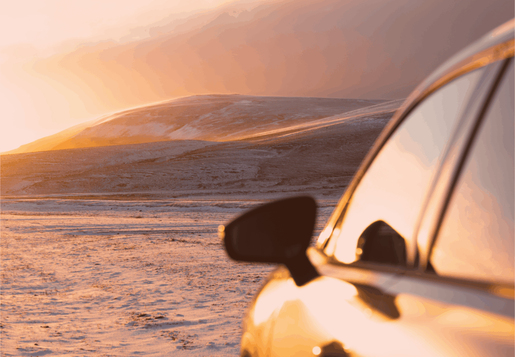 Close-up of rental car reflecting sunrise over snowy mountains in Iceland — Thrifty Car Rental Iceland winter road trip.